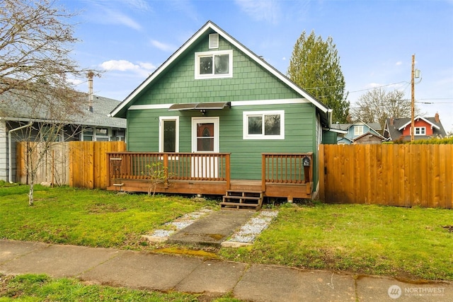 view of front of home featuring a wooden deck, a front yard, and fence