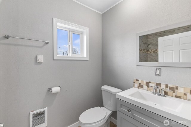 bathroom featuring toilet, ornamental molding, heating unit, decorative backsplash, and vanity