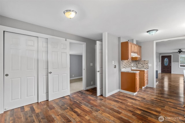 kitchen with under cabinet range hood, dark wood finished floors, light countertops, decorative backsplash, and ceiling fan