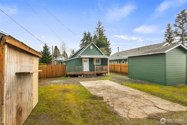 rear view of property with an outbuilding, a patio, and fence