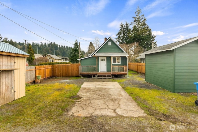 rear view of property featuring an outdoor structure, a fenced backyard, and a wooden deck