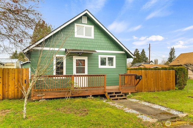 rear view of property with a deck, a yard, and fence