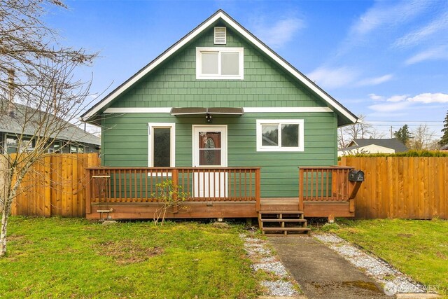 rear view of house featuring a deck, fence, and a lawn