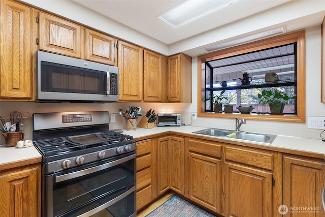 kitchen with light countertops, a toaster, appliances with stainless steel finishes, and a sink