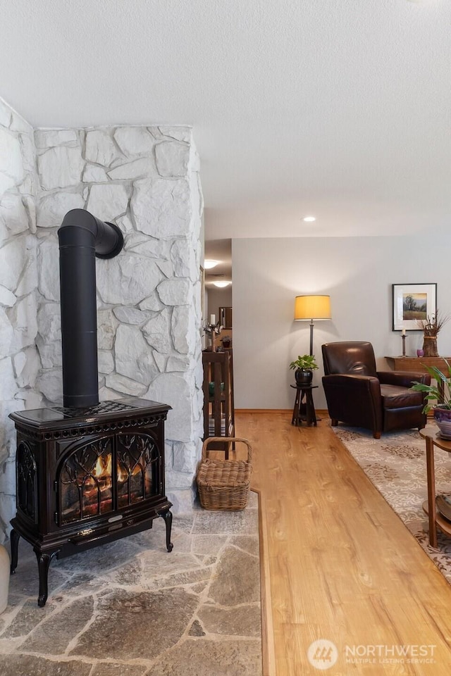 room details featuring a textured ceiling, a wood stove, and wood finished floors