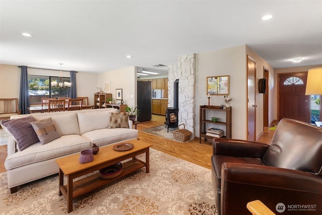 living room with visible vents, a wood stove, recessed lighting, light wood-type flooring, and a chandelier