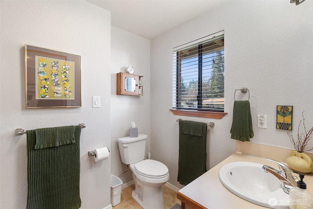 half bathroom with baseboards, toilet, and vanity