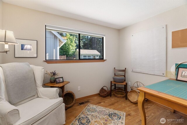 sitting room with wood finished floors, visible vents, and baseboards