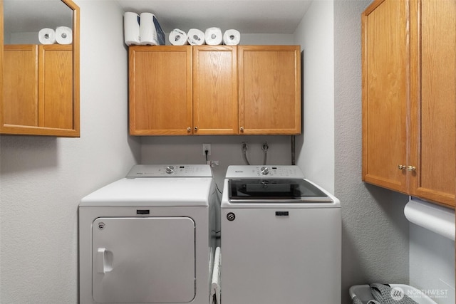 washroom featuring cabinet space and washer and clothes dryer