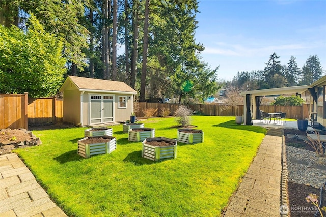 view of yard with an outbuilding, a fenced backyard, a shed, and a vegetable garden