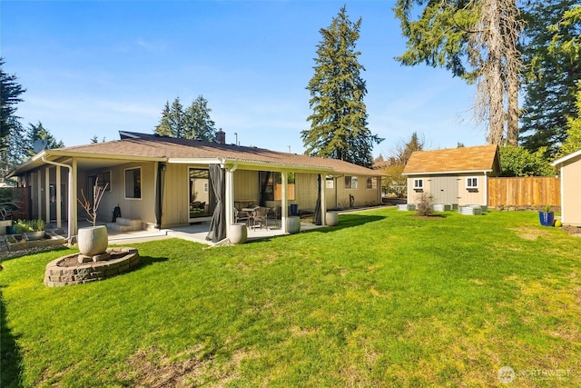 back of property with fence, a shed, a lawn, an outdoor structure, and a patio