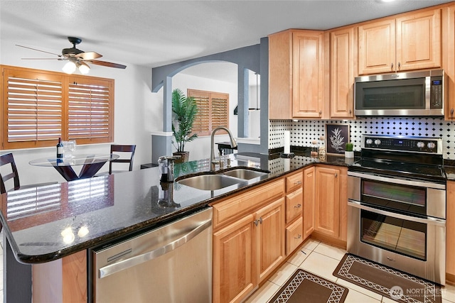 20417 Pugh Rd NE, Poulsbo, WA 98370 - kitchen featuring stainless steel appliances, a sink, a ceiling fan, arched walkways, and dark stone countertops