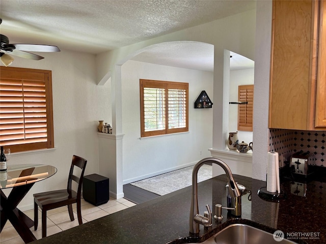 20417 Pugh Rd NE, Poulsbo, WA 98370 - kitchen featuring arched walkways, a ceiling fan, light tile patterned floors, a sink, and a textured ceiling