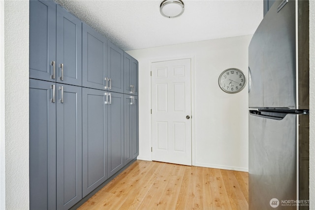 interior space featuring light wood finished floors, a textured ceiling, and baseboards