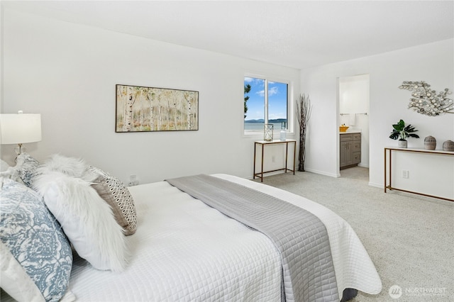 bedroom featuring baseboards, ensuite bathroom, and light carpet