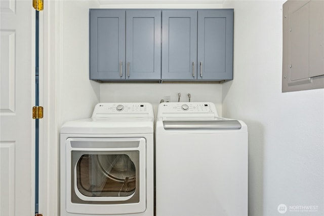 clothes washing area featuring electric panel, washing machine and dryer, and cabinet space