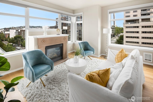 living area with visible vents, wood finished floors, baseboards, and a glass covered fireplace