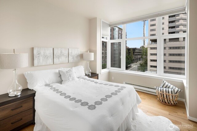 bedroom featuring wood finished floors, baseboards, and baseboard heating