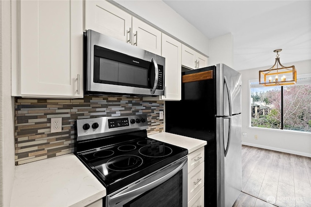 kitchen with decorative backsplash, white cabinets, a notable chandelier, and appliances with stainless steel finishes