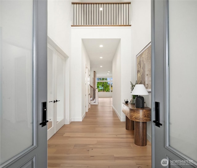 entryway featuring recessed lighting, light wood-style floors, baseboards, and a towering ceiling