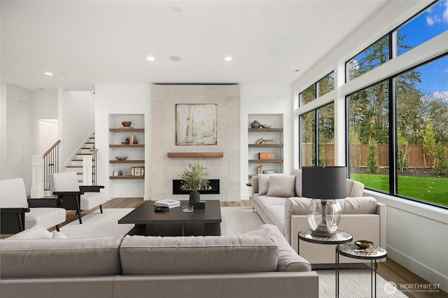 living area featuring recessed lighting, built in shelves, baseboards, and wood finished floors