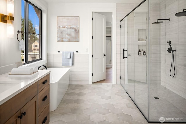 bathroom featuring tile patterned floors, a freestanding tub, tile walls, a shower stall, and vanity