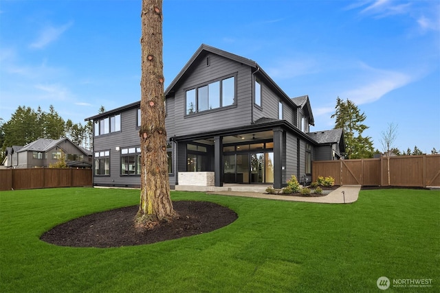 back of house with fence, a lawn, a sunroom, a patio area, and a gate