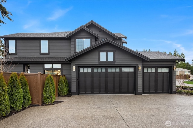 view of front facade featuring a shingled roof, concrete driveway, an attached garage, and fence