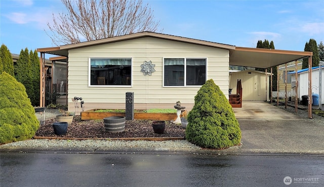 manufactured / mobile home featuring an attached carport, a garden, an outbuilding, and driveway