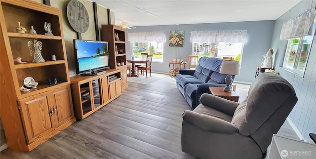 living area featuring baseboards, wood finished floors, and a ceiling fan