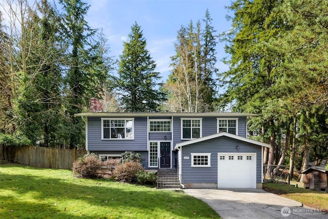 bi-level home featuring driveway, fence, a front yard, a garage, and a chimney