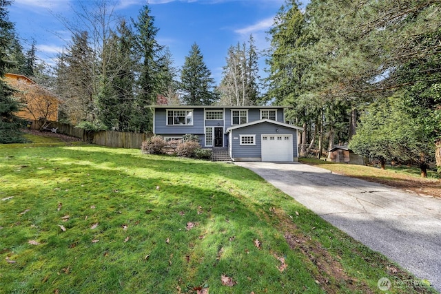 bi-level home featuring concrete driveway, a front yard, and fence