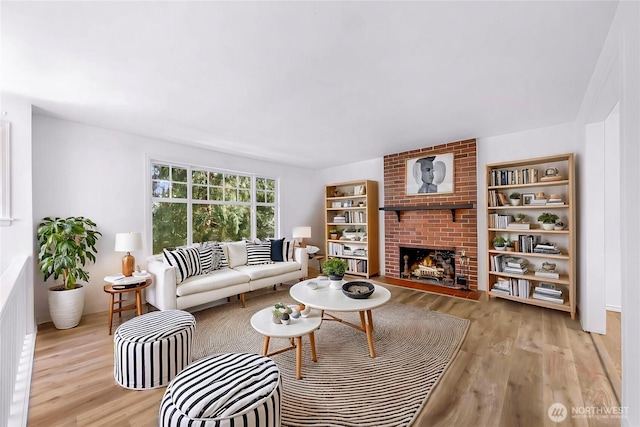 living room with light wood-type flooring and a brick fireplace