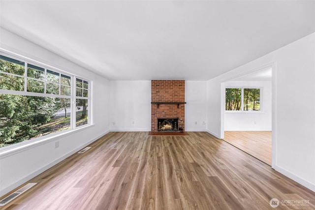 unfurnished living room with visible vents, baseboards, wood finished floors, and a fireplace