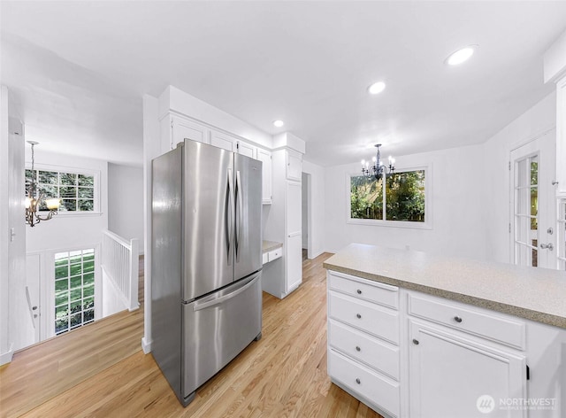 kitchen with freestanding refrigerator, light wood-style floors, an inviting chandelier, white cabinets, and light countertops