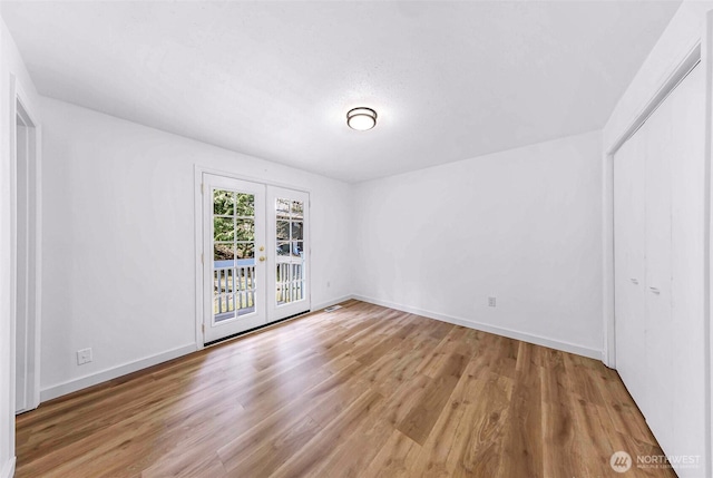 unfurnished room with french doors, baseboards, and wood finished floors