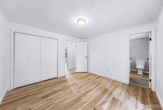 unfurnished bedroom with a closet, baseboards, light wood-style flooring, and ensuite bathroom