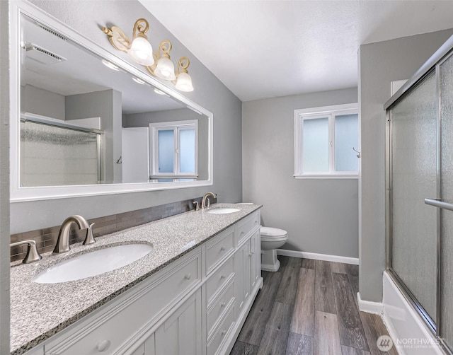 full bath with a sink, baseboards, a shower with door, and wood finished floors