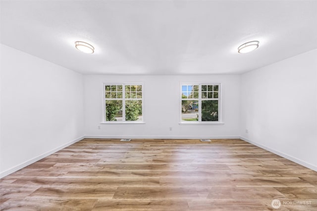 empty room featuring visible vents, wood finished floors, and baseboards