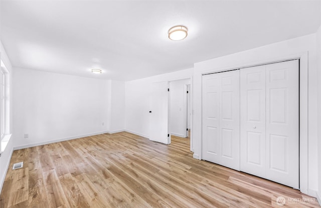 unfurnished bedroom with visible vents, baseboards, light wood-style floors, and a closet