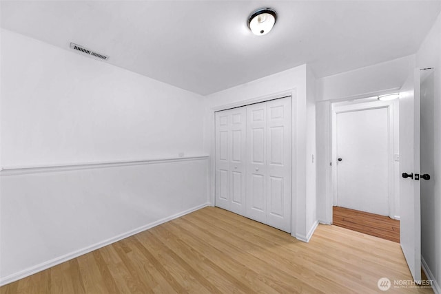 unfurnished bedroom with visible vents, baseboards, a closet, and light wood finished floors