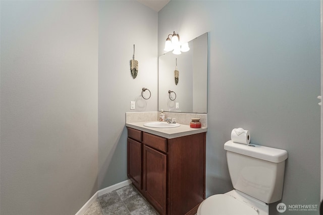 bathroom with toilet, vanity, and baseboards