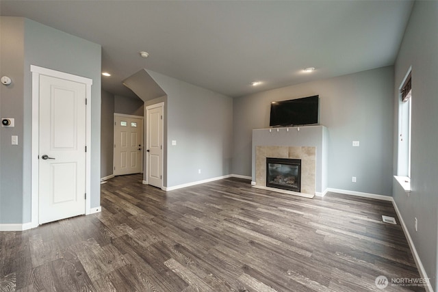 unfurnished living room featuring baseboards, visible vents, dark wood finished floors, recessed lighting, and a tiled fireplace