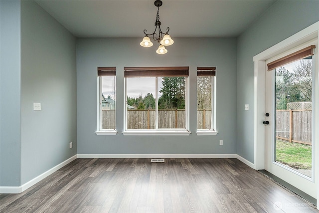 unfurnished dining area with baseboards, a healthy amount of sunlight, and dark wood-style flooring