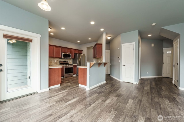 kitchen featuring a peninsula, a breakfast bar area, dark wood-style floors, and appliances with stainless steel finishes