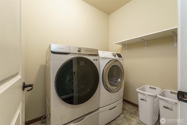 clothes washing area with washer and dryer, baseboards, and laundry area