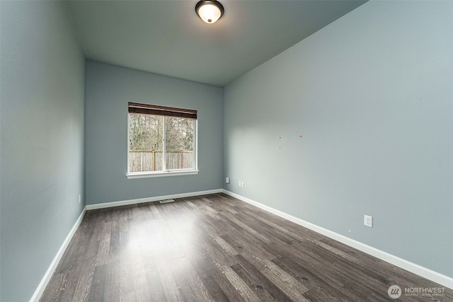 empty room featuring dark wood-type flooring and baseboards