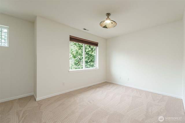 unfurnished room with a wealth of natural light, visible vents, baseboards, and light colored carpet