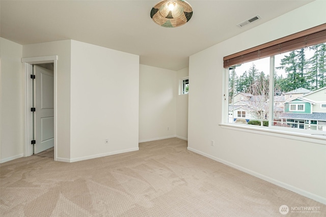 unfurnished room featuring visible vents, baseboards, and light colored carpet