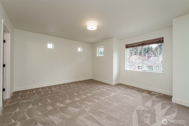 unfurnished room featuring a wealth of natural light, visible vents, baseboards, and carpet floors